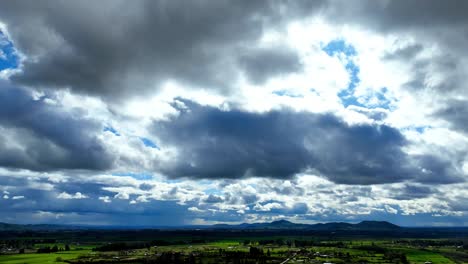 Wolken-Im-Zeitraffer-über-Grüner-Landschaft-Und-Kleinen-Bergen-Am-Horizont