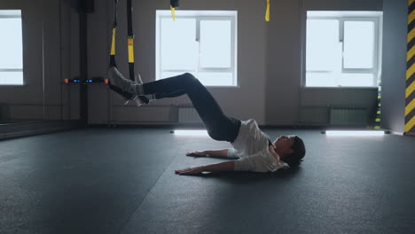 doing trx exercises. young athletic woman in sports clothing training legs with trx fitness straps in the gym. exercise where stabilizing muscles trained and the whole body is working truly functional