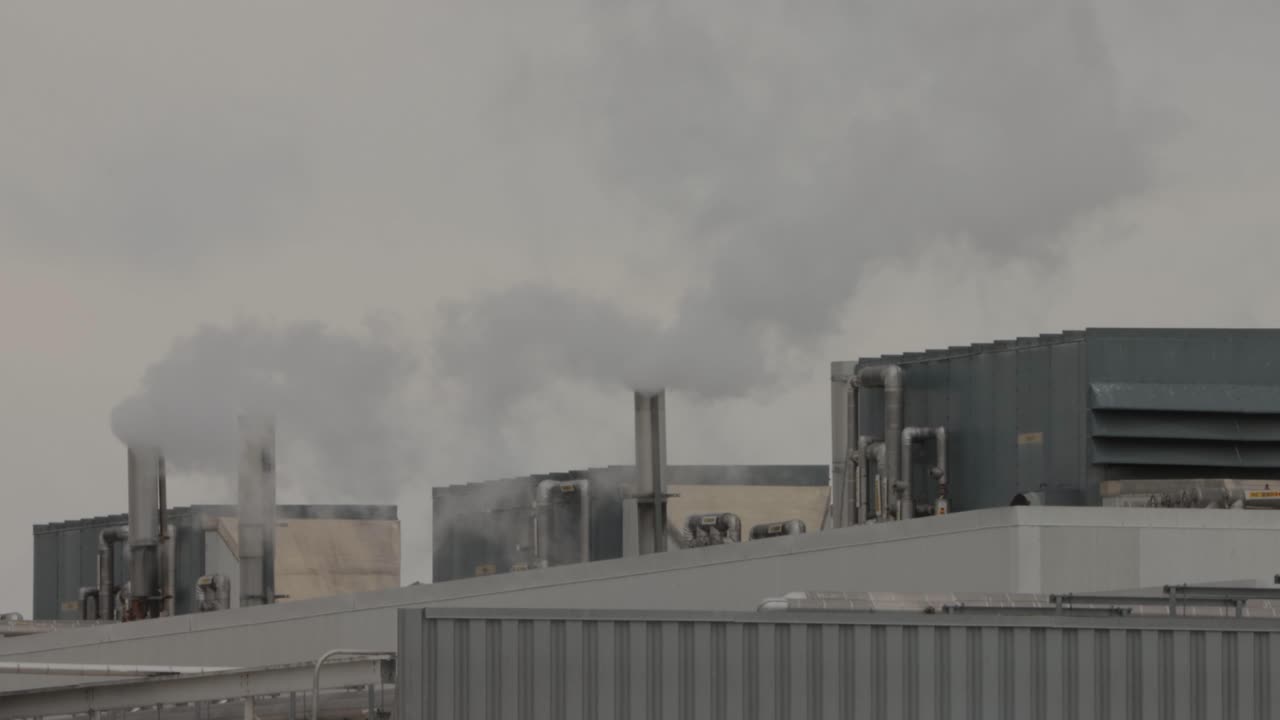 pilas industriales que emiten vapor en una atmósfera contaminada con edificios circundantes
