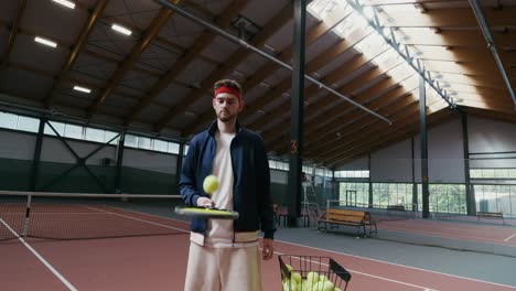 man practicing tennis in an indoor court