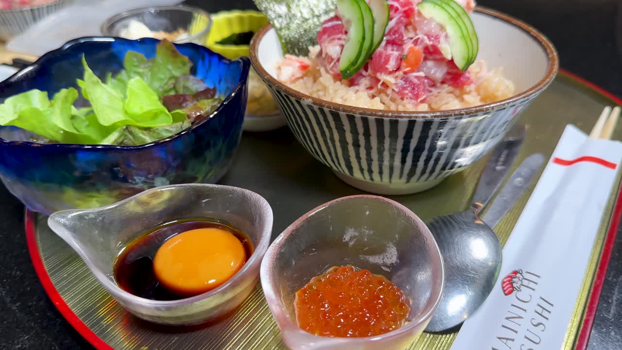 Ein Koch stellt eine traditionelle japanische Meeresfrüchteschale zur Essensausgabe auf die Theke eines Restaurants