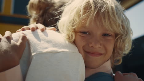 Closeup-school-boy-hugging-mom-at-yellow-bus.-Schoolboy-saying-goodbye-to-mother