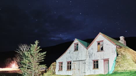 Leuchtende-Sterne-Am-Abendhimmel-über-Hölzernen-Rasenhäusern-In-Südisland