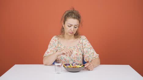 person looking at vegetable on fork with unhappy expression. difficulty dieting.