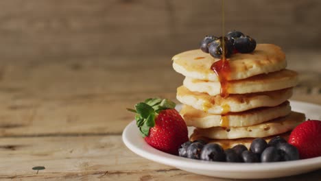 Video-of-maple-syrup-pouring-into-pancakes-with-fruits-on-wooden-background