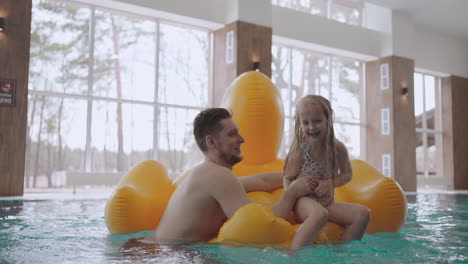 Un-Hombre-Adulto-Y-Su-Pequeña-Hija-Nadan-En-La-Piscina.-La-Niña-Está-Sentada-En-Un-Divertido-Pato-Inflable.