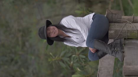 video vertical de vaquera latina riendo y sentada en la cerca