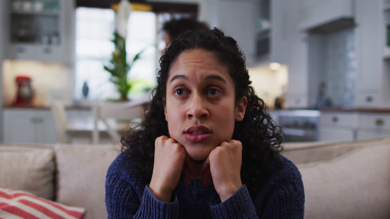Mixed race woman sitting on couch and looking annoyed