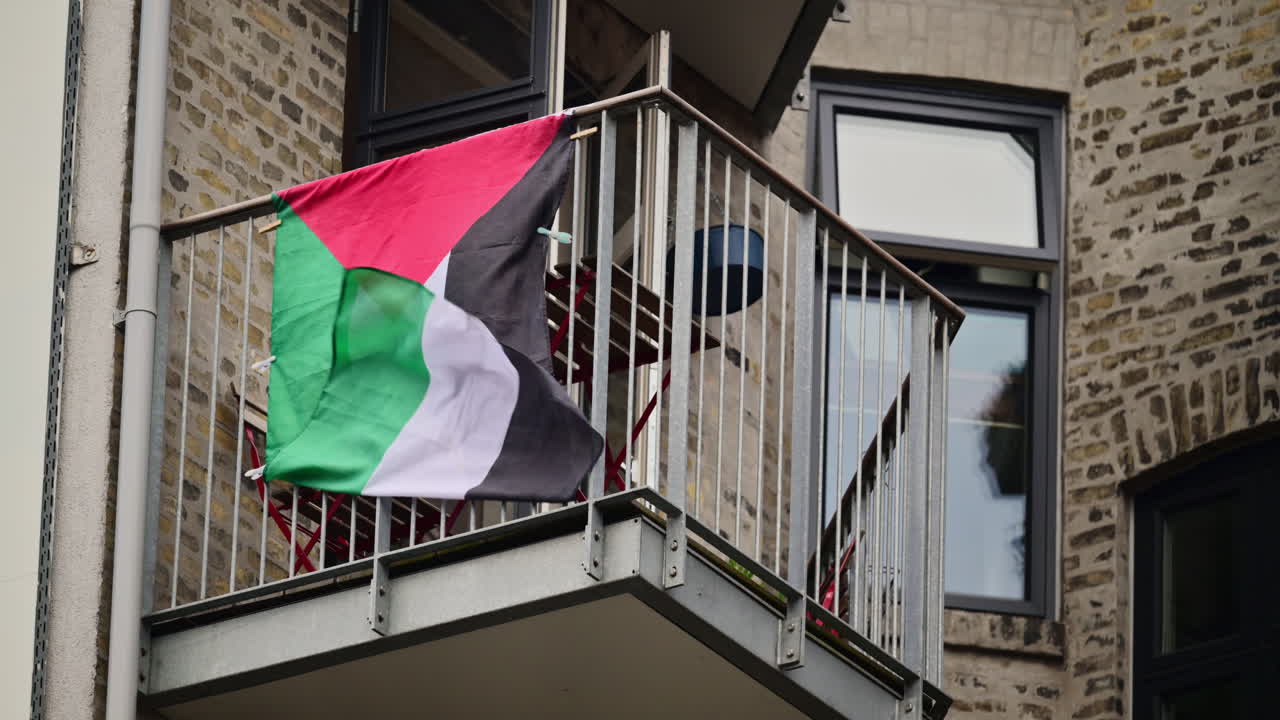 Bandiera palestinese che sventola dal balcone di un edificio residenziale, a simboleggiare il sostegno