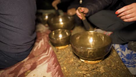 tapping the sides of the tibetan singing bowls with a wooden hammer, a ritual that enhances healing and deep meditation through the ethereal tones coming from the musical instrument