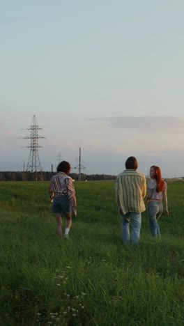 friends walking in a field at sunset