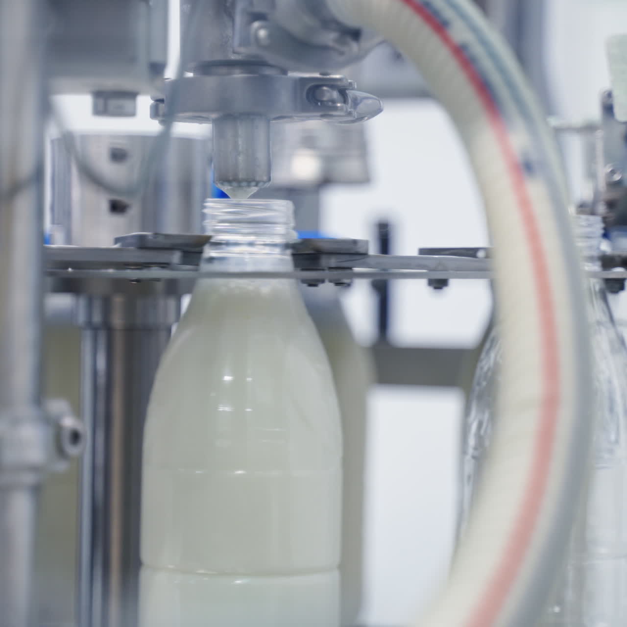 Automated technology of bottling milk in robotic factory. Plastic bottles are filling with milk by modern machinery at a dairy plant. Close-up.