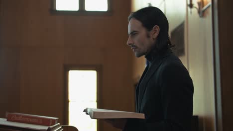 young christian pastor in church preaching from pulpit with bible