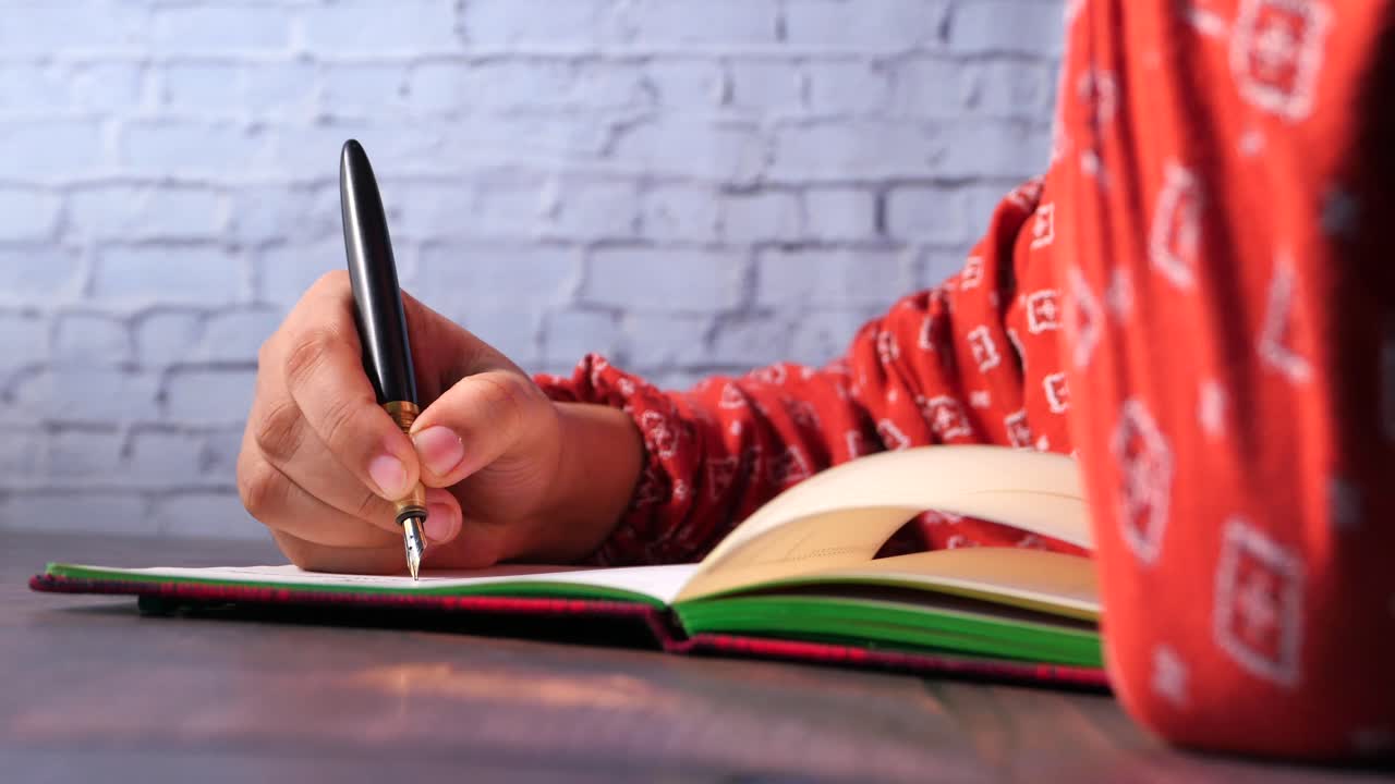 Person Writing in a Notebook with a Fountain Pen