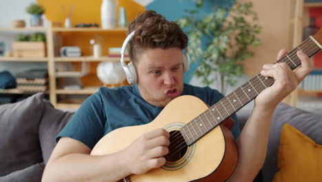 man playing acoustic guitar on couch