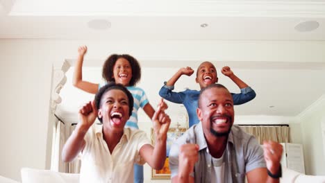 kids and parents cheering while watching match on television in living room