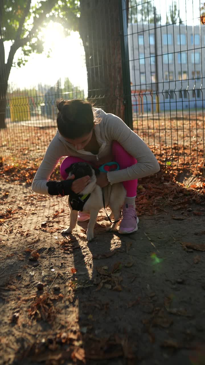mujer jugando con su cachorro pug en un parque