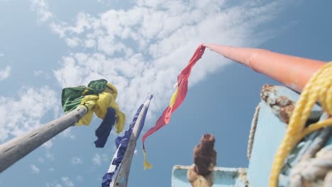 colourful flags on mast of small indian fishing boat flying in the see wind slow motion