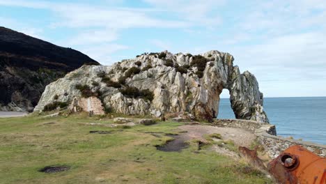 red rusted industrial mill tank abandoned on welsh rock archway coastline