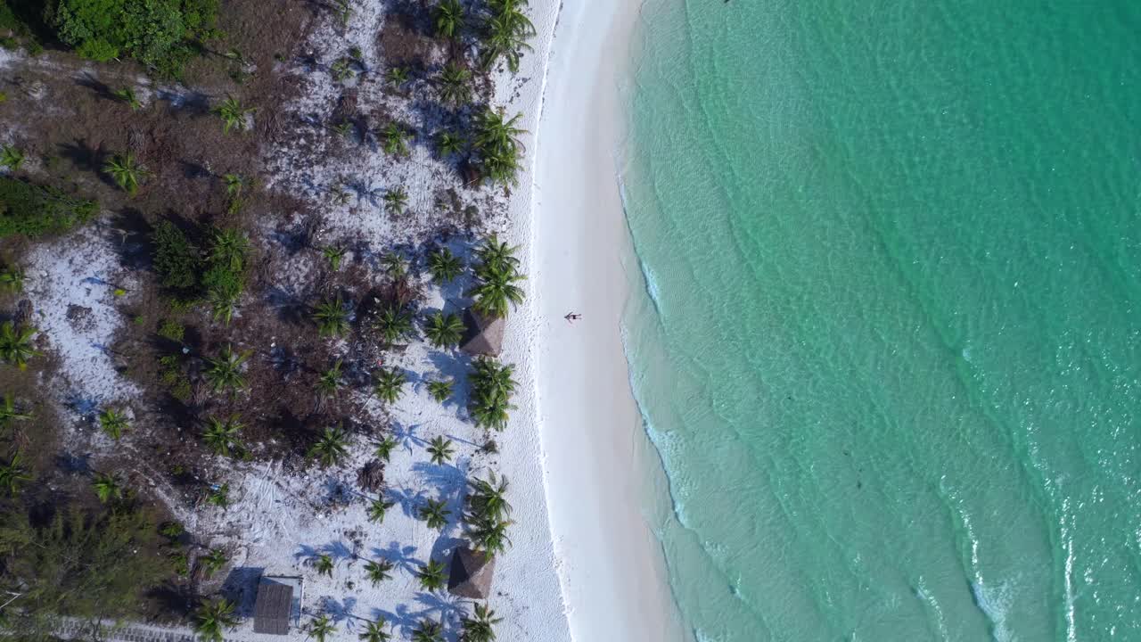Tourist lying on a beautiful tropical beach, enjoying the sun and the sound of the waves. Best aerial view flight vertical bird's eye view drone