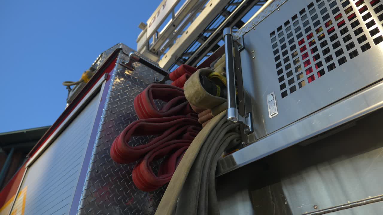 Manichette antincendio su un'autopompa lucida all'alba, fuori da una stazione dei pompieri.