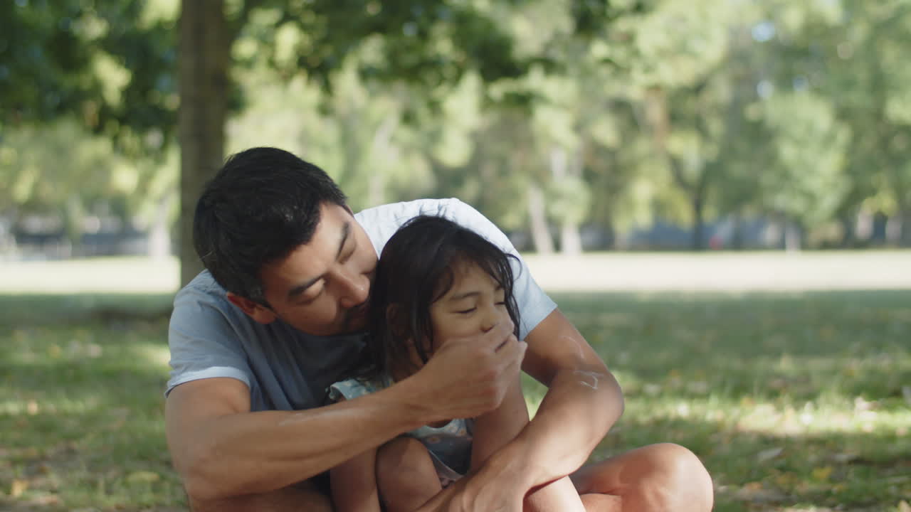 hombre feliz sentado con su hija en el parque y coloreando sus narices