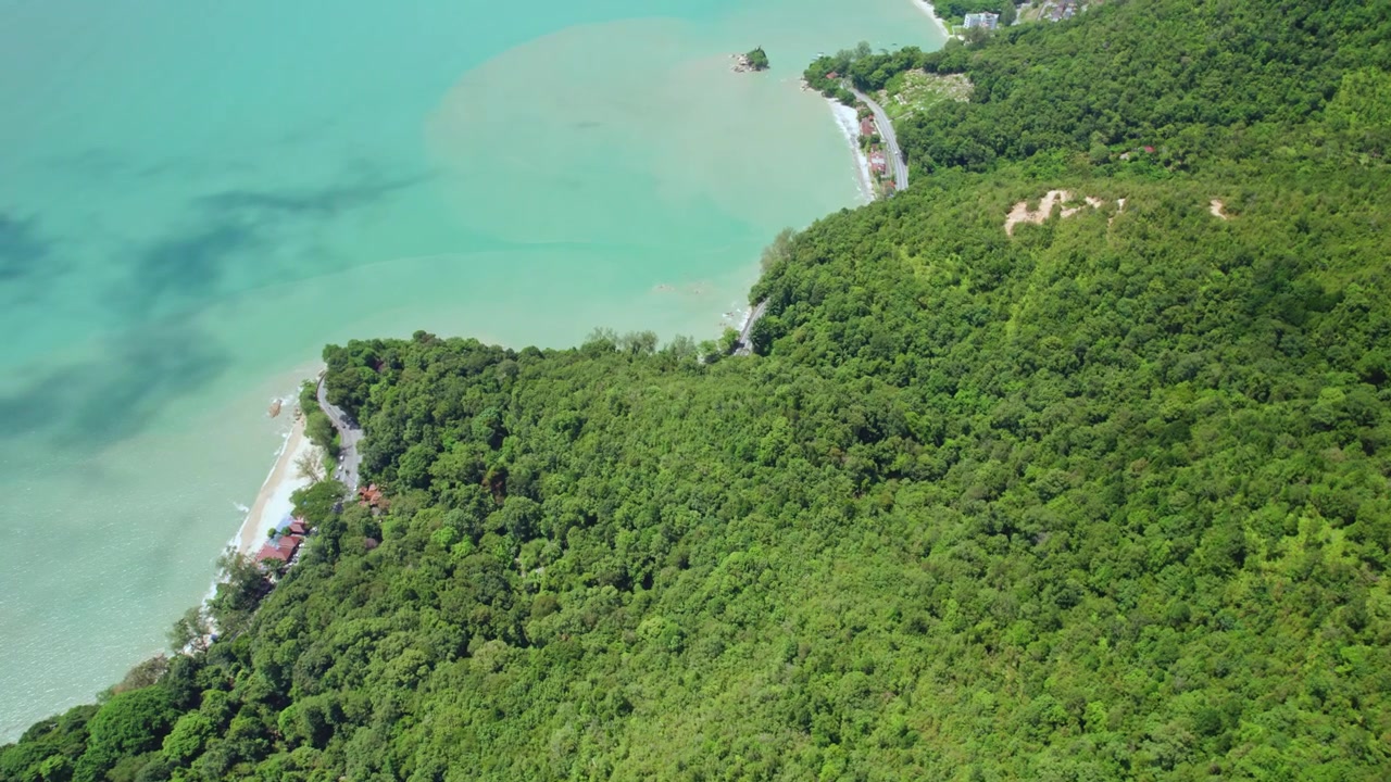 Dynamic aerial view of Penang Island showcasing a dramatic tropical mountainscape descending directly into turquoise sea along the Malaysian coastline.
