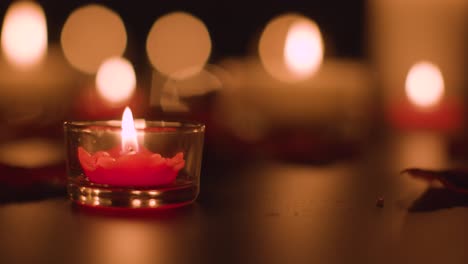 primer plano de velas rojas y blancas iluminadas románticamente ardiendo sobre un fondo negro con iluminación bokeh 3