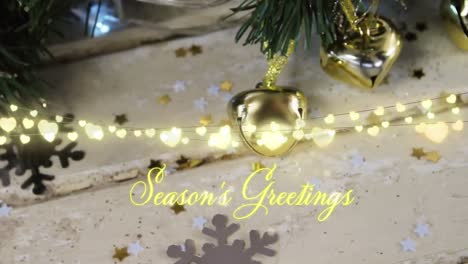 animation of text, season's greetings, in yellow, over string lights and christmas tree decorations