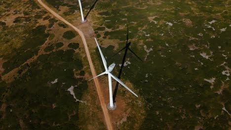 aerial establishing shot of wind turbines staggered along a dirt track in france