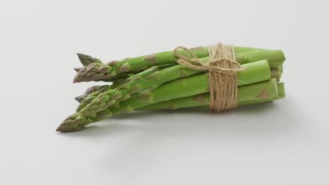 video of close up of bundle of fresh asparagus over white background