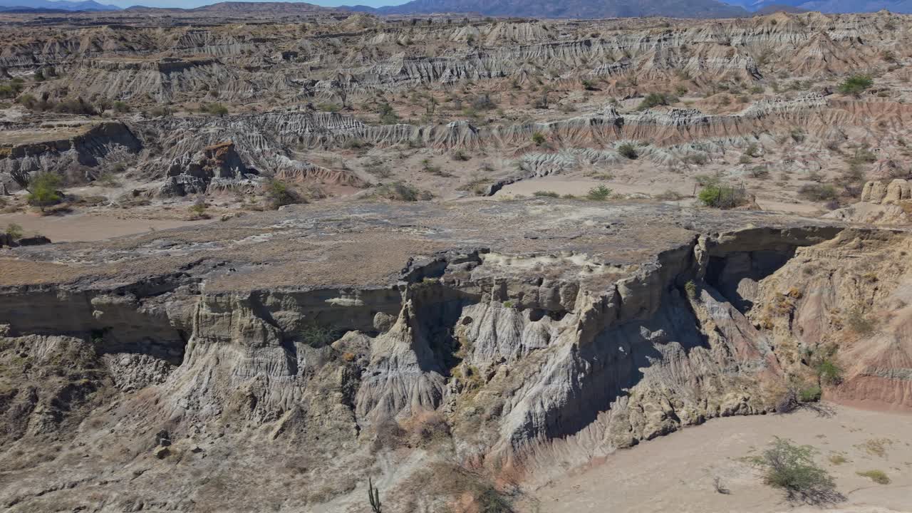 Drone-opname met lage snelheid van een droge rivierbedding in een ander deel van de Colombiaanse Tatacoa Grey Desert, met unieke erosieformaties en gelaagde kleuren grijs, rood en oranje