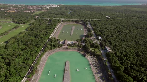 Filmischer-Drohnenclip,-Der-über-Zwei-Kreisförmige-Wasserreservoirs-Inmitten-üppiger-Vegetation-Fliegt