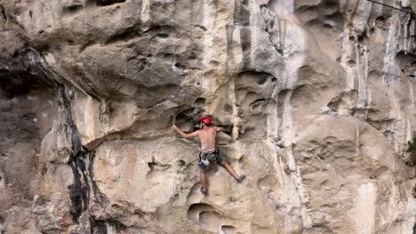 male rock climber belaying rope on harness hook on karst mountain, aerial