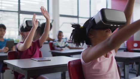 diverse schoolchildren sitting in classroom wearing and using virtual reality glasses