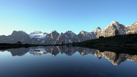 Wanderer-Geht-Am-Ufer-Eines-Gletschersees-Mit-Eisbedeckten-Bergen-Entlang