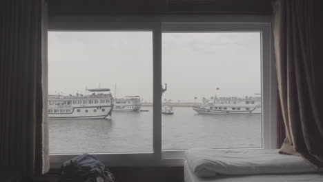 shot from inside a sleep boat in vietnam near halong bay on a cloudy day with other boats seen through the window log