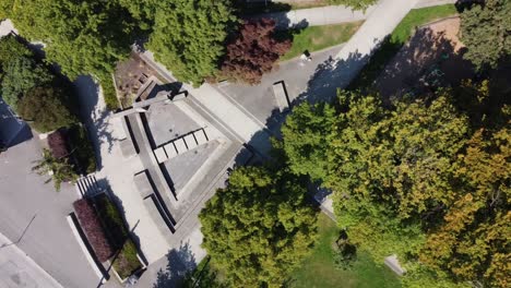 aerial-birds-eye-view-over-empty-modern-futuristic-park-at-a-metroplolis-with-empty-steps-leading-to-a-dry-contemperary-stylish-fountain-water-sprinklers-in-the-summer-where-its-sunny-lush-green-3-3