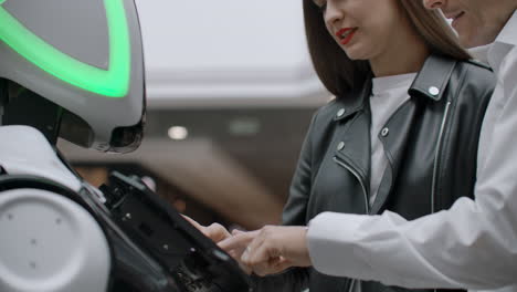 the couple communicates with robot assistant with information screen in duty to give information. contact with the robot and interaction with help systems.