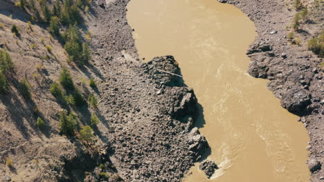 Vista-De-Pájaro-Aéreo-Del-Río-Marrón-Que-Fluye-A-Través-Del-Desfiladero-Del-Valle-Rocoso