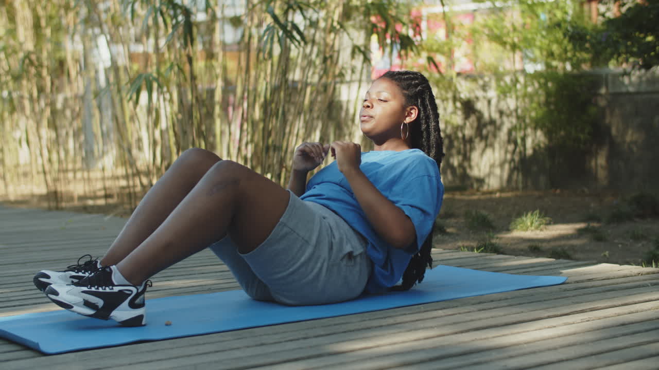 una foto estática de una mujer gorda haciendo abdominales en un parque de verano.