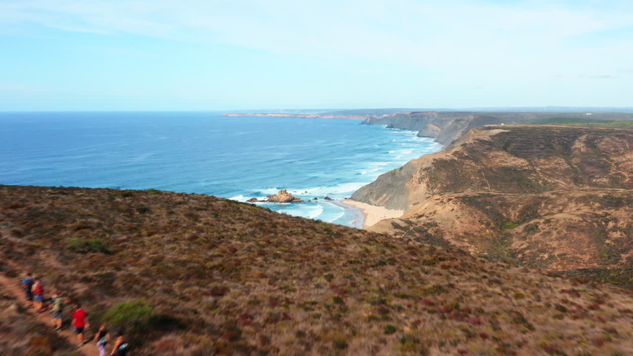 Aerial flyover mountain with hiker group and beautiful atlantic ocean landscape with sandy beach in background