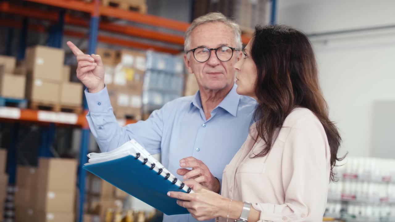 mujer madura y hombre analizando documentos en el almacén.