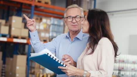 mature woman and man analyzing documents in the warehouse.