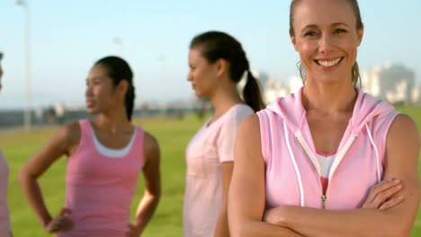 Mujer-Sonriente-Vestida-De-Rosa-Por-Cáncer-De-Mama-Frente-A-Sus-Amigos.