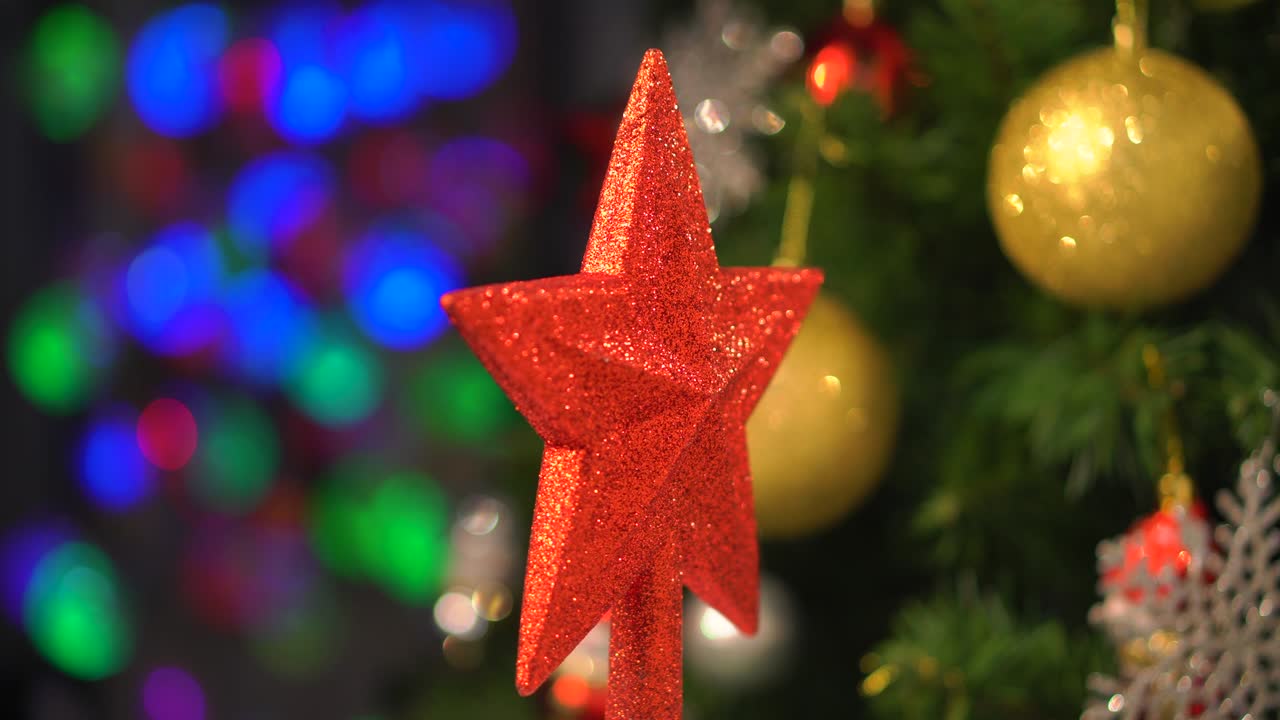 decoraciones de estrella de navidad rojas ornamento girando en el árbol de navidad y borrosas luces bokeh fondo, bola de oro.