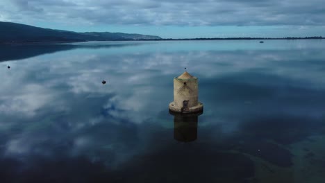 old spanish mill in the lagoon at old island town orbetello near monte argentario and the maremma nature park in tuscany, italy, with blue sky and calm blue water