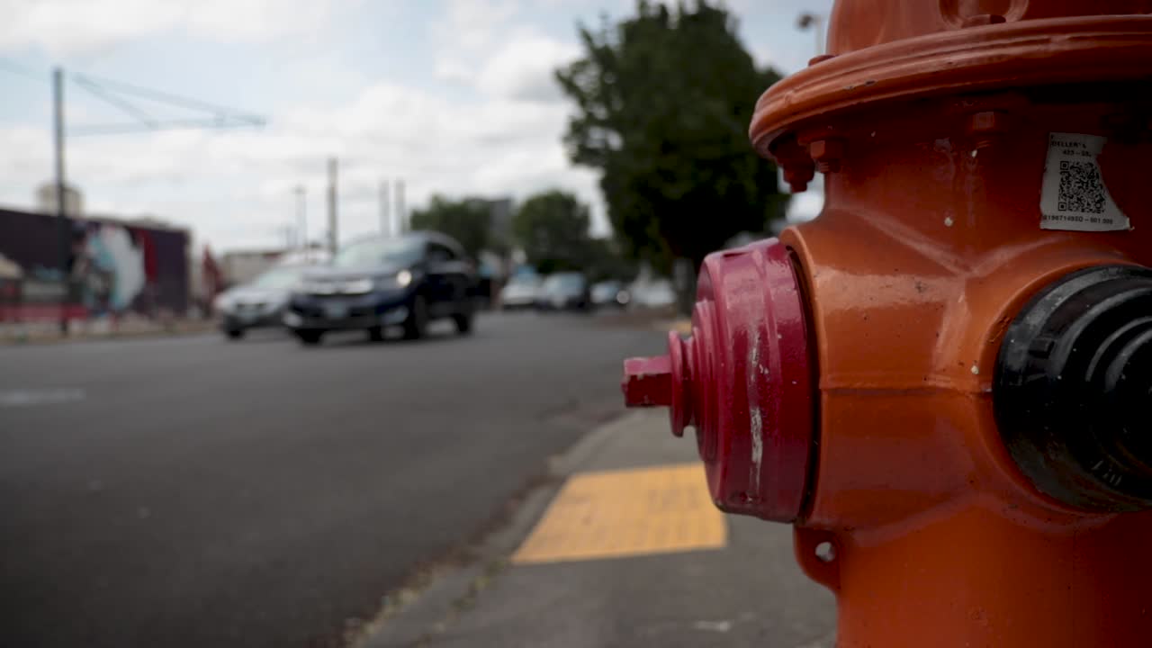 close up of a red fire hydrant with out of focus traffic behind it. Hand Held.