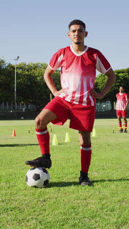 video vertical de un jugador de fútbol biracial en el campo con la pelota