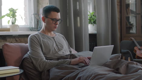 freelancer working on laptop from bed